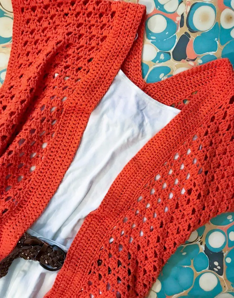 orange crochet cardigan over white shirt