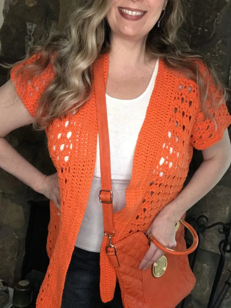 orange crochet cotton cardigan over a white tank top on woman