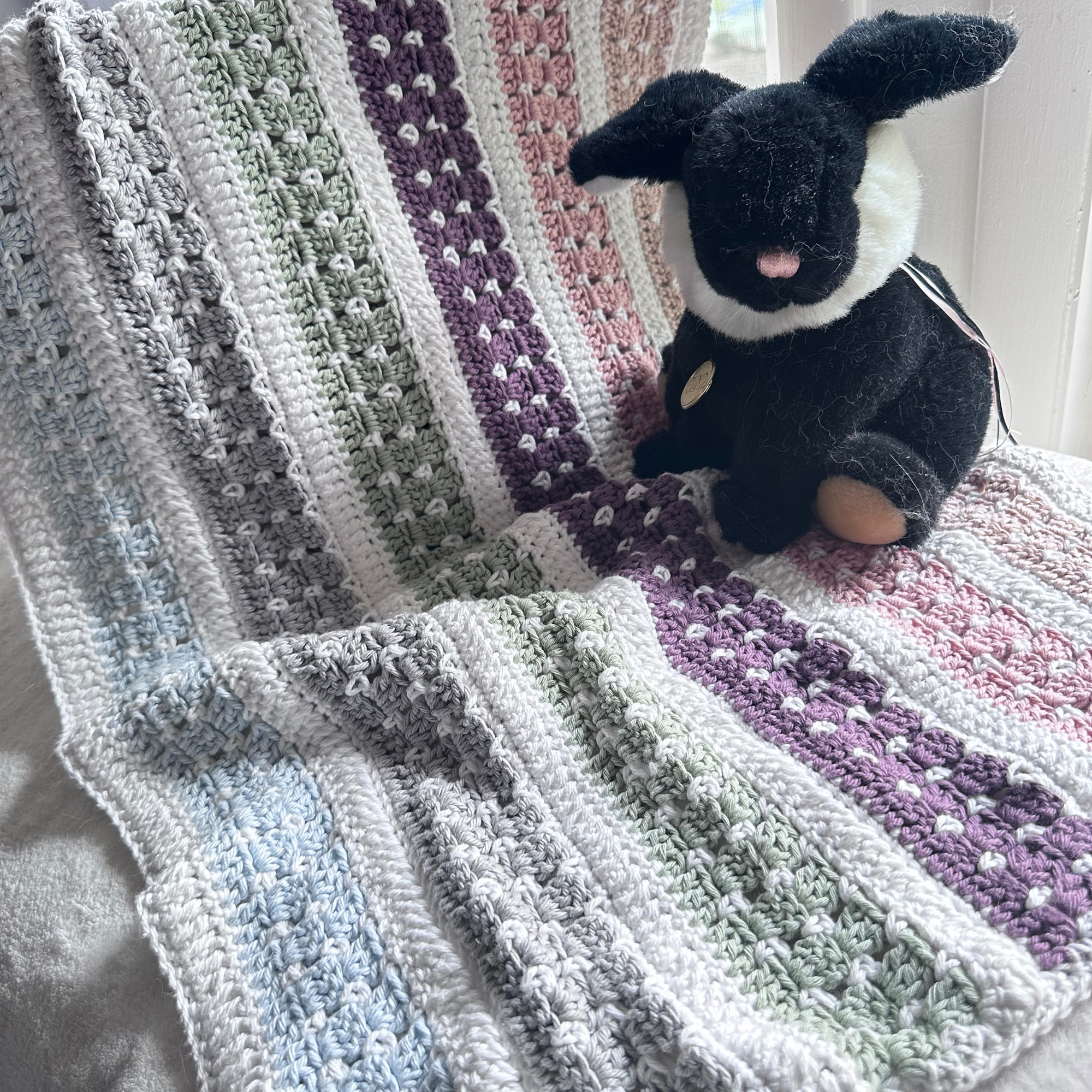 rainbow crochet baby blanket pattern with a tri color bunny toy on top
