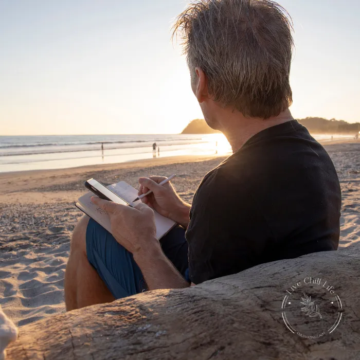 man writing next to ocean