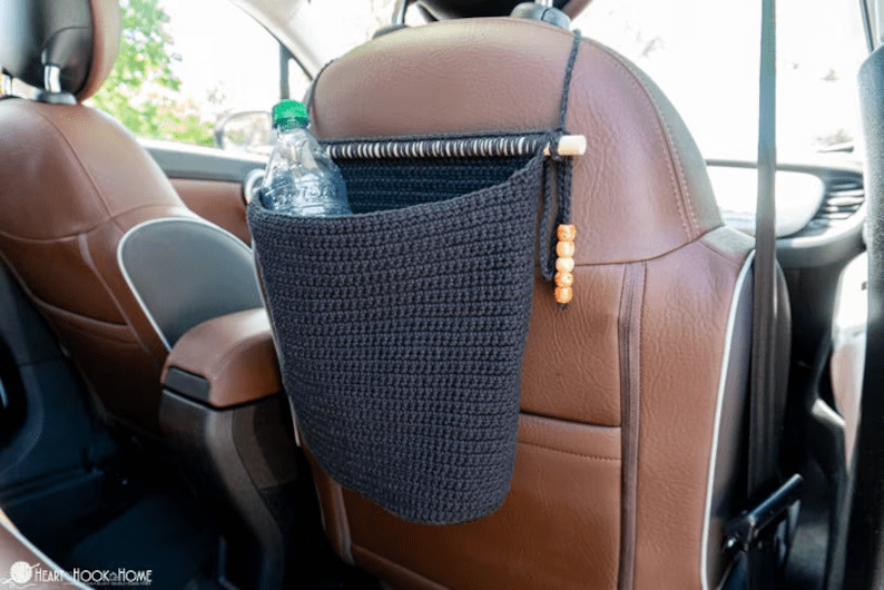 a crochet trash organizer secured over a passenger car seat.