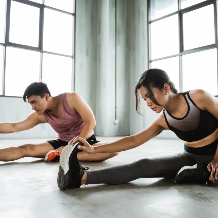 man and woman stretching on floor wearing fitness attire