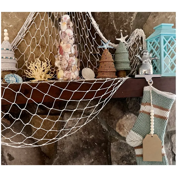 seashell tree, fisherman's net and crochet christmas items on hearth