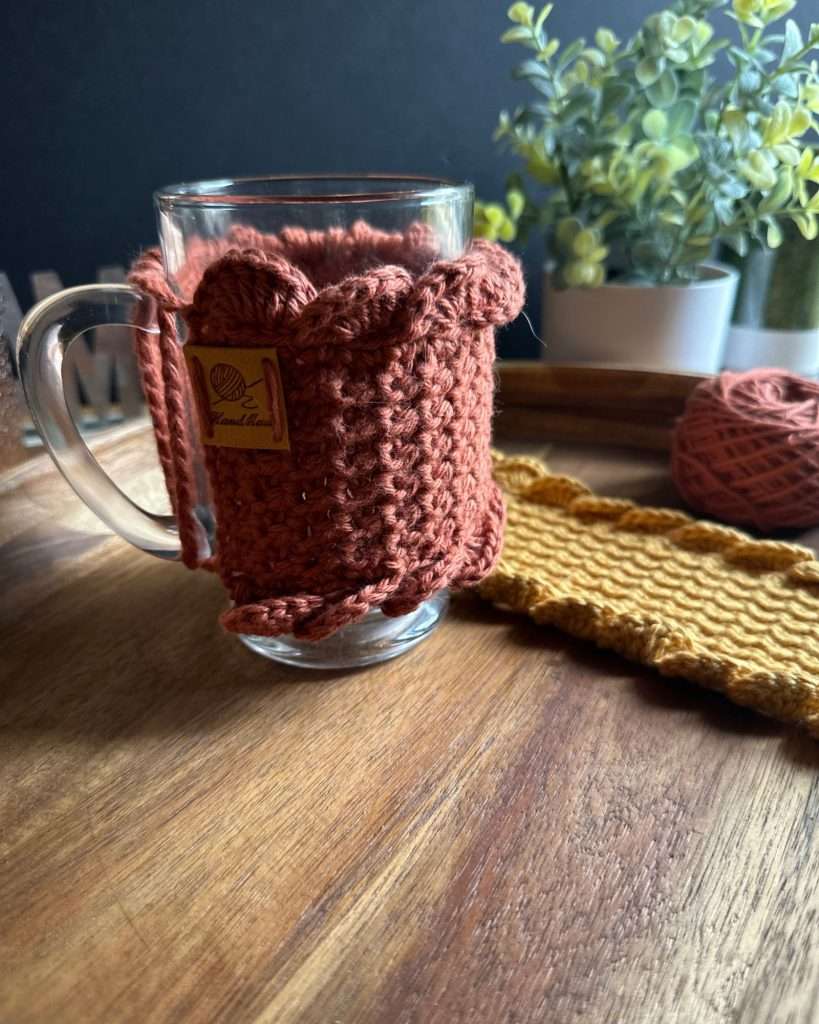 Crochet mug cozy on a glass mug with a green plant in background