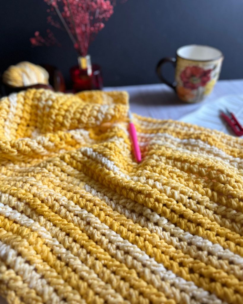 chunky yarn blanket with textured stitches made with yellow gradient yarn