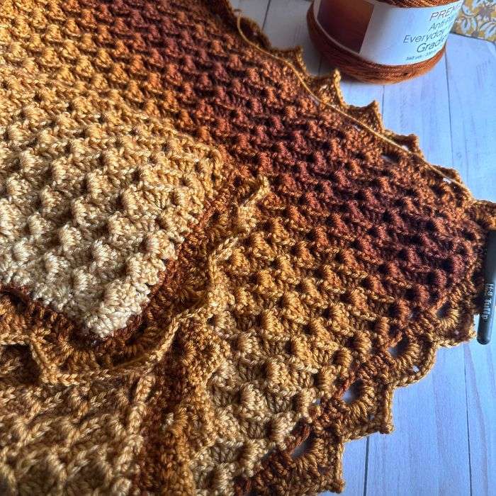 cluster stitch crochet blanket made with gold and brown gradient yarn with a fall aesthetic